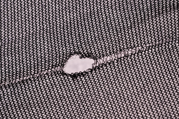 Black knitted mesh textile with irregular tear and soft background