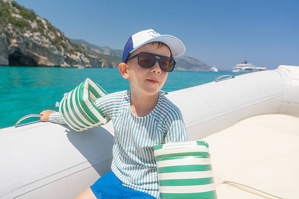 A young boy steers a longtail boat during an excursion on a canal in Thailand