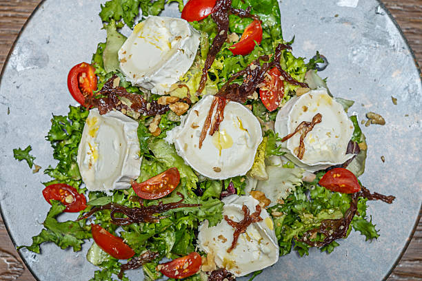 A green salad with a Mediterranean touch, where arugula and lamb's lettuce are mixed with black olives, feta cheese cubes, and a dressing of extra virgin olive oil and oregano.