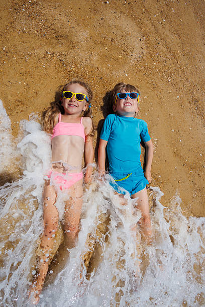 istock Kids in glasses enjoying waves on a sunny beach day together 2256135791