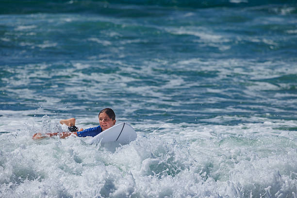 Happy surfer teen trying to balance on their board wait for ocean waves during surf lesson