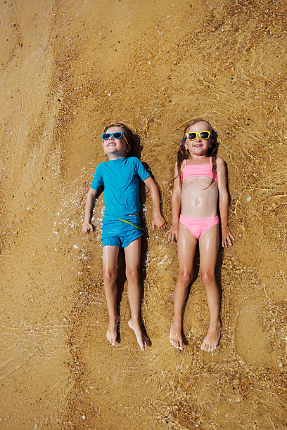 istock Happy kids laying in shallow water at beach under summer sun 2256135818