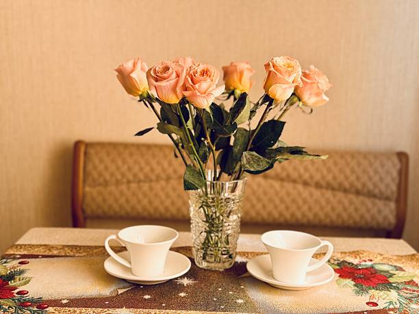 A coffee cup sits on a saucer beside a bouquet of purple and white flowers, creating a beautiful contrast of drinkware and natures beauty