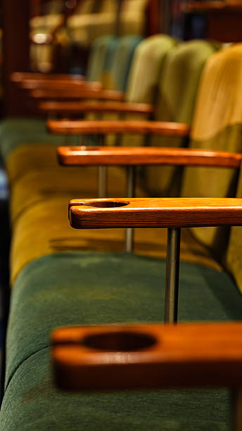 Empty theater seats with wooden armrests and cup holders waiting for an audience