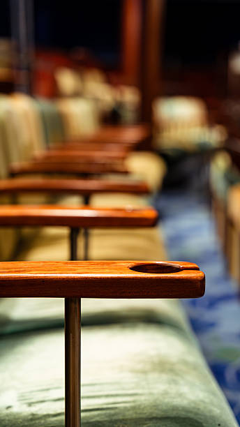 Row of cushioned theater chairs with dark wooden armrests and cup holders