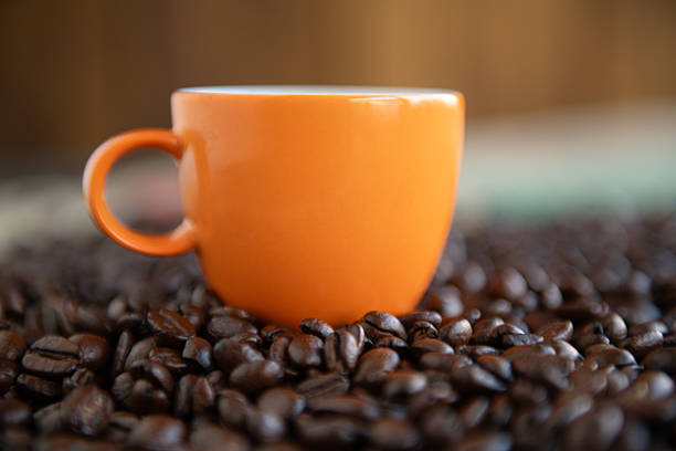 A white cup of coffee and scattered coffee beans.