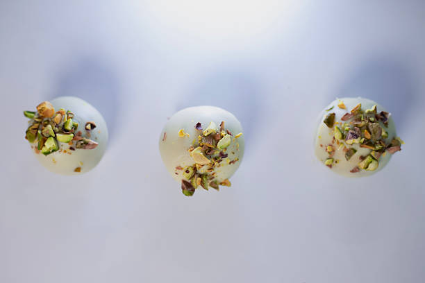 Cake balls with pistachio topping arranged in a straight line on a white surface