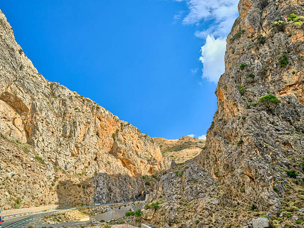 Crete landscape in Greece showcases rugged mountains, rocky hills, and an arid hillside beneath a bright blue sky with white clouds. This natural outdoor scene highlights Greek terrain and scenery, perfect for travel, nature, tourism, and adventure stock projects celebrating Crete and Greece.