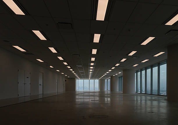 Bangkok, thailand - 11 Oct, 2025 -  In a large, empty room where floor-to-ceiling windows frame a panoramic city skyline view, a polished, reflective floor and a grid of ceiling lights define the office space. Copy space, Selective focus.