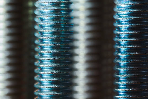 Detailed view of metallic screw threads with blue lighting and shallow depth of field