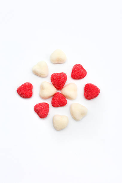 Heart shaped gummy candies in red and white colors arranged on a clean white background