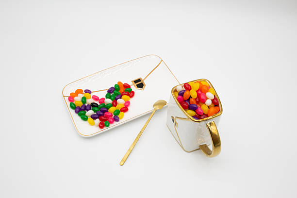 Colorful jelly beans forming a heart on an elegant white plate with a mug of candy