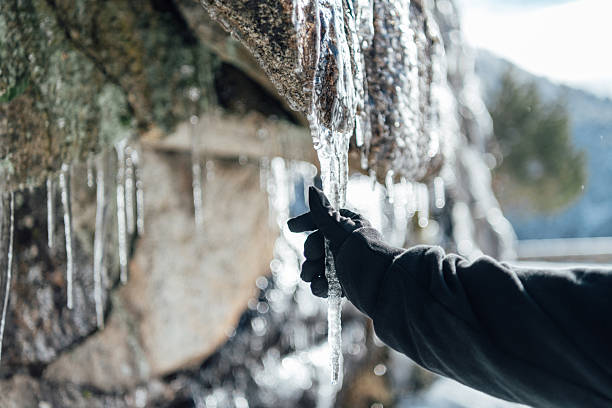 Hand with a winter glove picking up a heart-shaped stone with a winter landscape behind. Tourism in Iceland