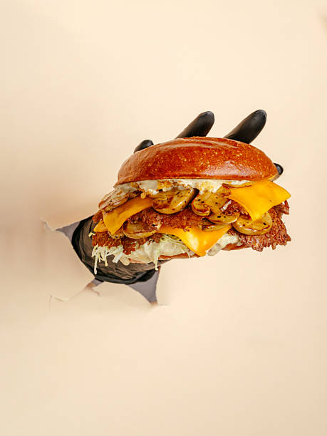 A person holding a sandwich with a bun and cheese
