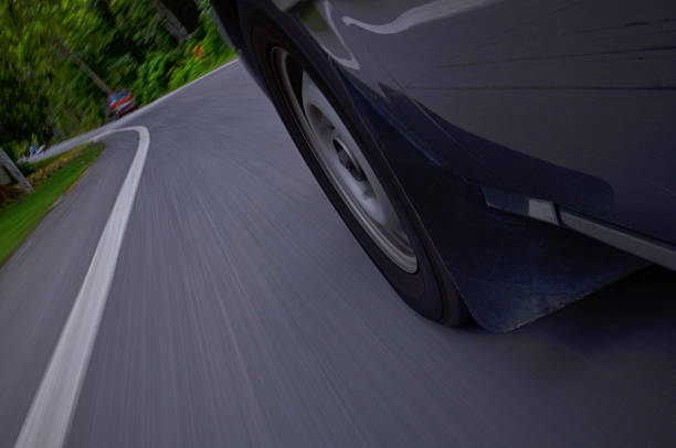 Close up of a grey luxury wheel of car , close up of the rear side of a black luxury car parked on an open road , Automotive concept