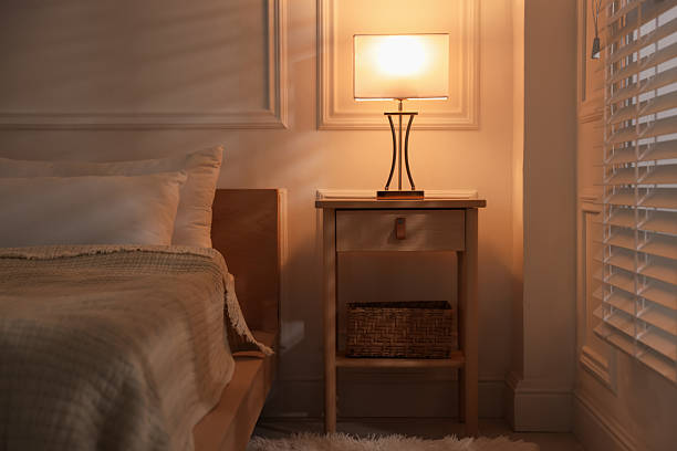 Bedside table with lamp near bed indoors