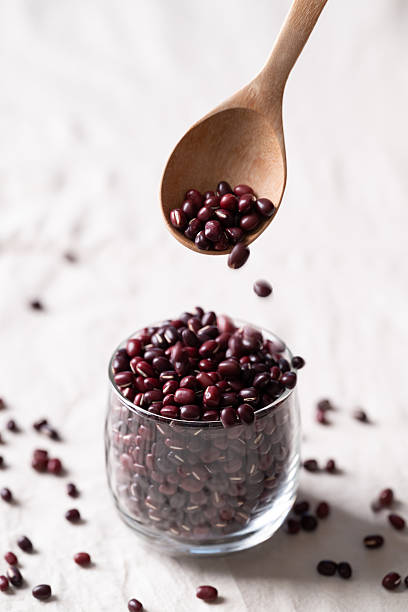 Azuki beans, Adzuki bean or red mung beans in glass with spoon on white fabric background