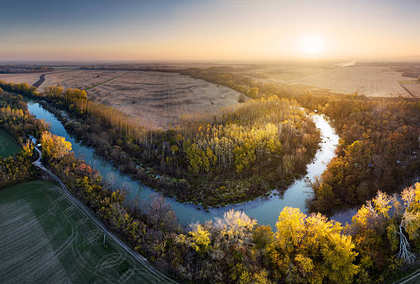Aerial landscape yellow autumn forest with meander small winding river with sun light, top view.