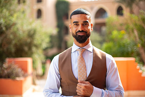 Confident man smiling at the camera, posing outdoors in a professional vest and tie
