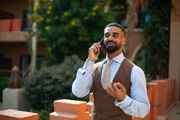 Smiling businessman talking on a cell phone while standing outside in formal wear