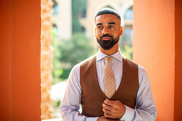 Professional man posing, adjusting his shirt sleeve, creating a confident and elegant feeling