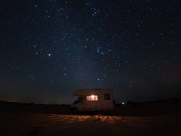 istock Night scene in the Douz desert, Tunisia, with a camper van illuminated from inside beneath a star-filled sky featuring the Orion constellation and bright Jupiter, creating a serene adventure mood 2256197185