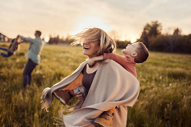 istock Cheerful mother piggybacking her son in nature at sunset. 2256201712