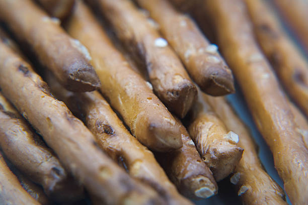 Soft and crispy pretzels are arranged neatly in a glass display at a bakery. The warm golden-brown pastries attract customers on a busy morning.