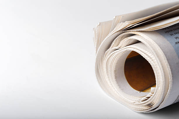 A roll of newspapers sits on a plain white background with visible rolled pages.