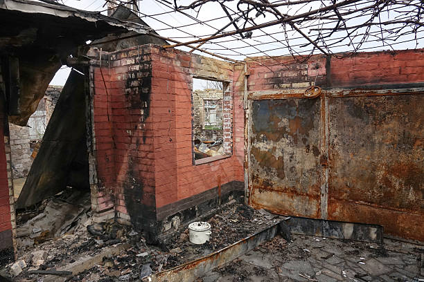 Abandoned burned brick garage interior with collapsed roof, rusty metal gates and fire damage, post-industrial ruin showing destruction, decay and dramatic aftermath