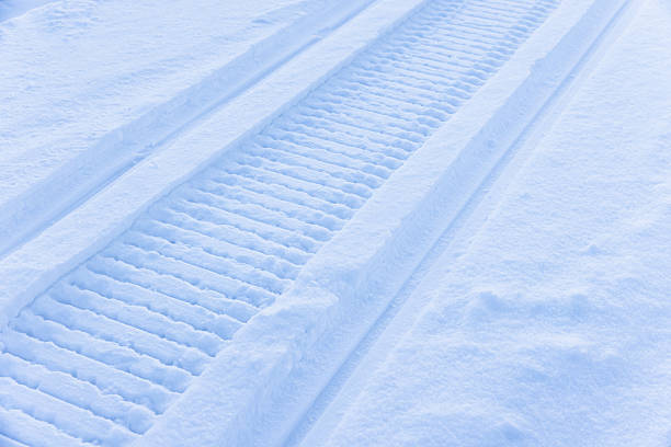 Snowmobile track stretches through a tranquil winter landscape. A cool blue tint enhances solitude and calm, inviting quiet reflection in a pristine snowy setting