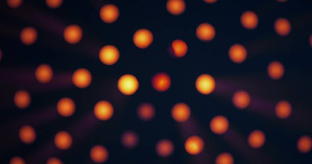 Warm yellow light shines through round holes in a black background. The intensity of the glow increases and decreases