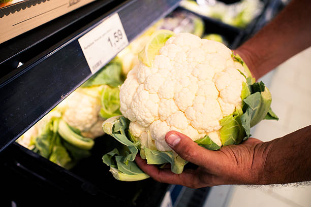 Hand holding a healthy organic cauliflower head in a supermarket