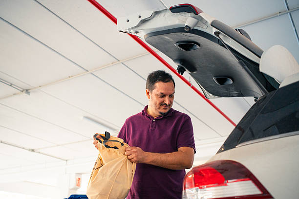 Man putting shopping bag into car trunk in parking garage