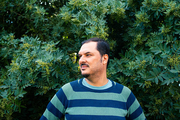 Adult man enjoying nature while looking away, green foliage in background