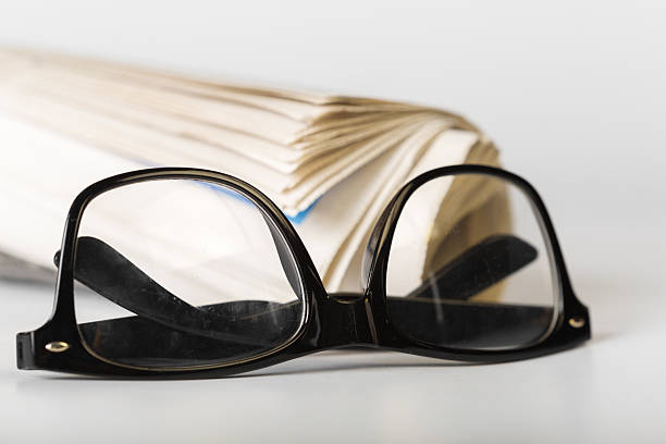 A closeup shot of a pair of reading glasses and a folded newspaper