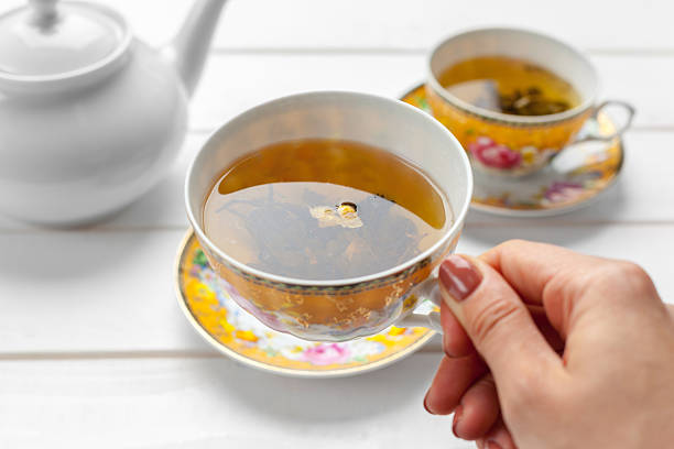 Still life featuring a porcelain teacup, metal teapot, and open book arranged on a decorative tablecloth, creating a cozy and inviting atmosphere