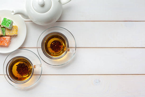 Tea and treats on a wooden table with sweets and a teapot in the afternoon light