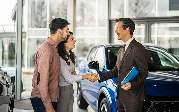 istock Car salesman shaking hands with happy couple 2256235081