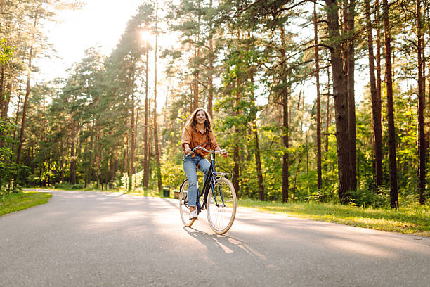 istock A young woman rides her bike along a sunny park path. 2256236231