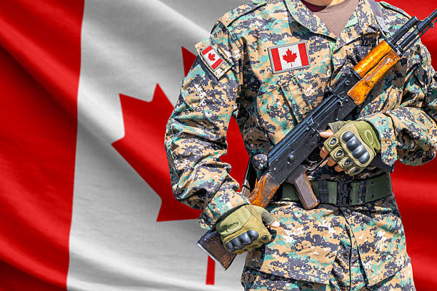 Canada flag with soldier in military uniform holding assault rifle in front of it