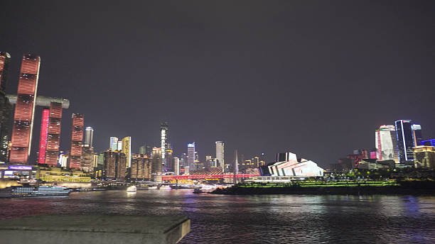Chongqing cityscape at night featuring brightly lit skyscrapers and bridges reflecting on the river. Urban skyline illuminated, showcasing modern architecture and vibrant nightlife.
