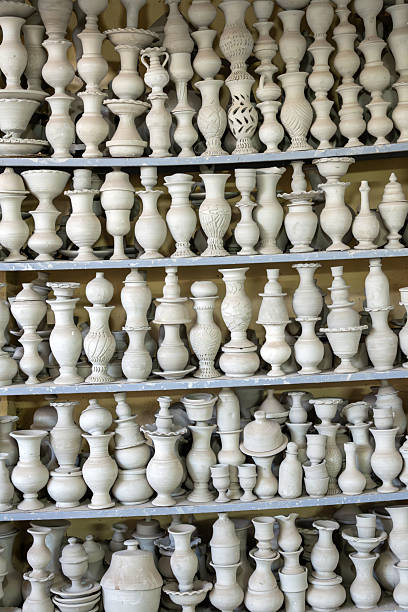 Densely packed display of white pottery on metal shelves in Fes, Morocco. Classic vase shapes, handmade craft, and warm light evoke traditional Moroccan artisan markets.