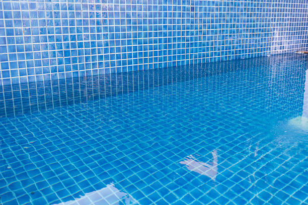 Water shows blue tiles in a swimming pool at a private home in sunlight.