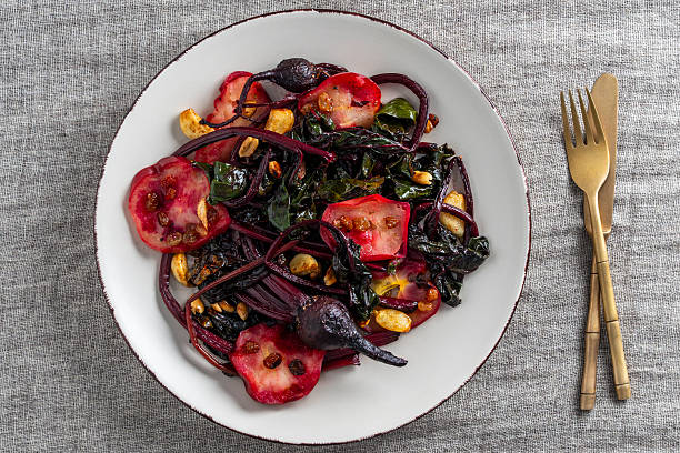 Delicious salad of roasted beetroot stalks with apples and peanuts, garlic and raisins