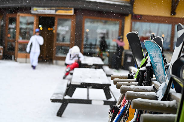 View of snowboards and skis seen at window of a wooden building.