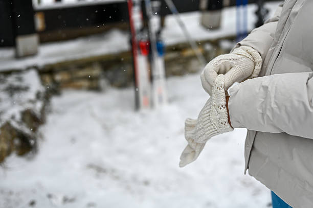 Woman putting on knitted gloves before skiing on a snowy winter day
