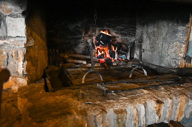 Logs burning in a rustic stone fireplace with embers glowing