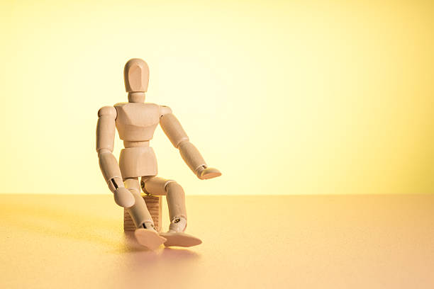 A wooden mannequin sits on a yellow background, waiting. free space for lettering and a wooden mannequin