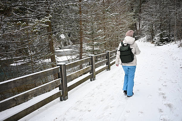 Adult hiking a snow-covered path alongside a river in a frozen winter forest
